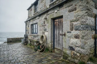 Façade authentique d'une maison de pêcheur bretonne en granite avec casiers à homard et porte en bois peinte en bleu marine