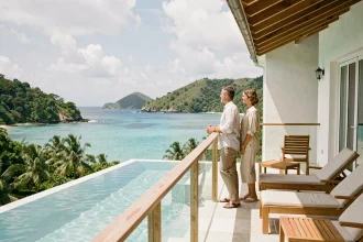 Couple en tenue décontractée sur la terrasse d'une villa de luxe à Saint-Barthélemy avec vue panoramique sur la baie turquoise